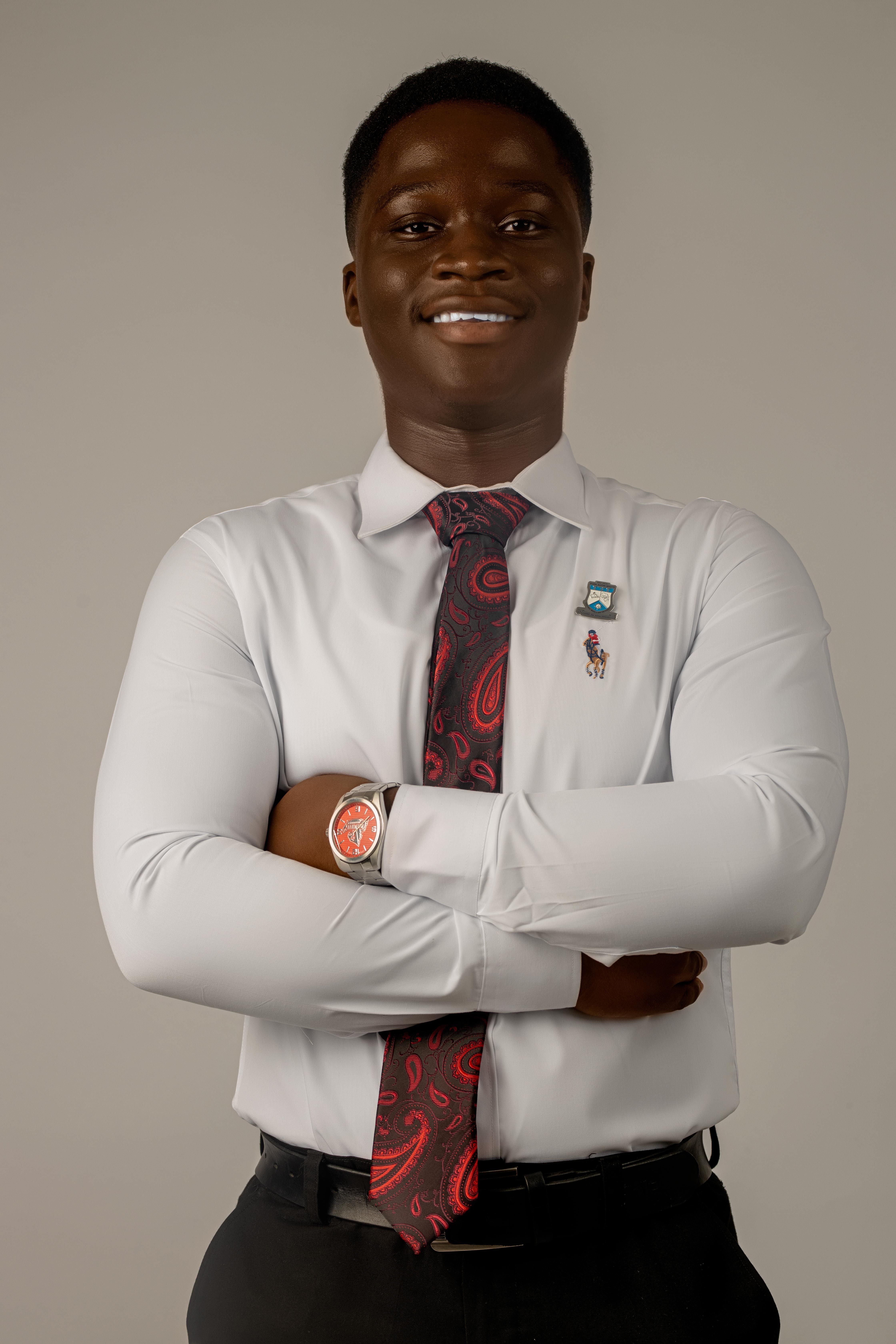 Young man in formal attire with a paisley tie and wristwatch, smiling confidently.