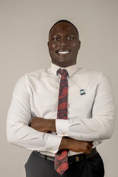 Smiling businessman with crossed arms in a white shirt and red tie, exuding confidence.