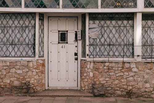 A white door with a window and a stone building