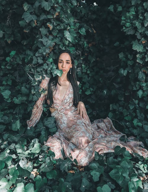 Woman Sitting in Dress among Leaves