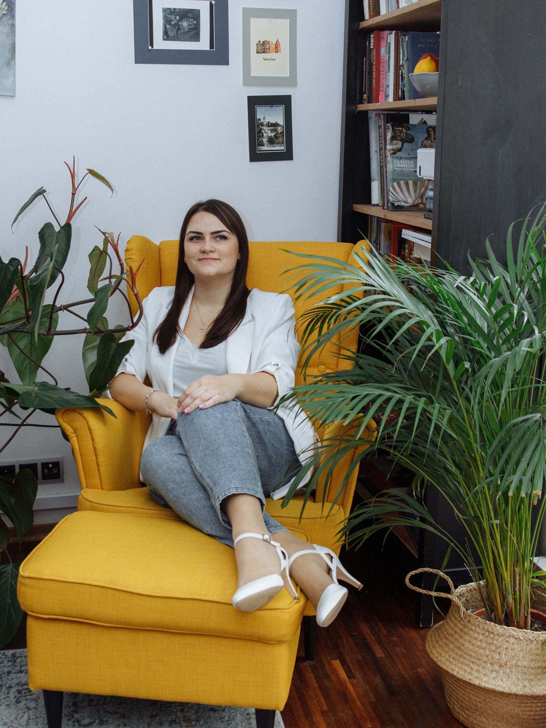 Woman in a modern living room with vibrant yellow armchair, surrounded by greenery.