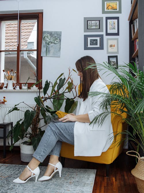 Woman Sitting in an Armchair and Using a Laptop 