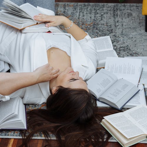 A woman laying on the floor with a pile of books