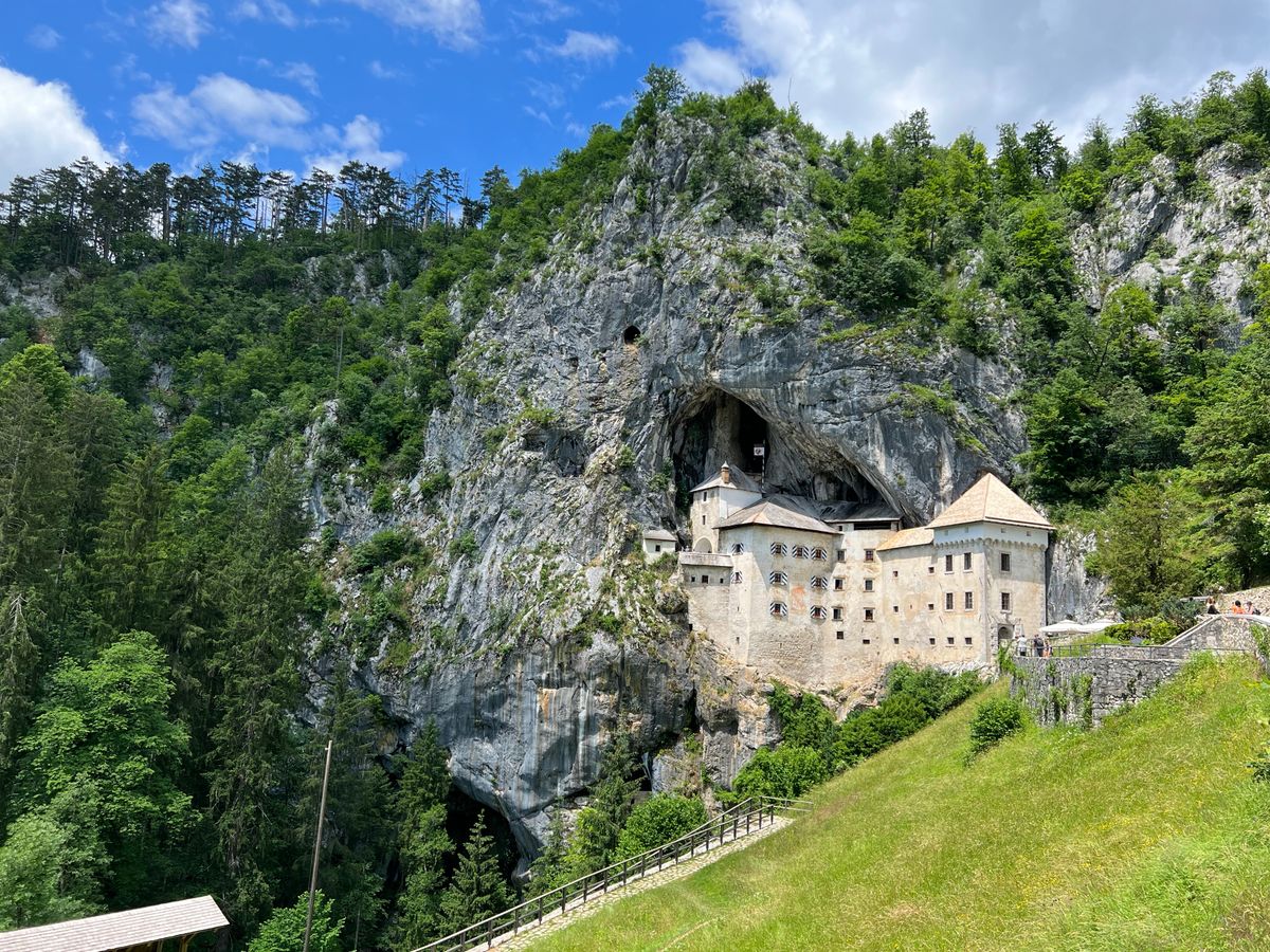 Predjama Castle built into a cliff face above green woodland