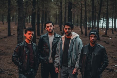 Free A group of men in stylish jackets posing confidently in a dense forest setting. Stock Photo