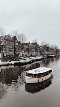 Explore Amsterdam's iconic canals with this tranquil view of historic buildings and a passing boat.