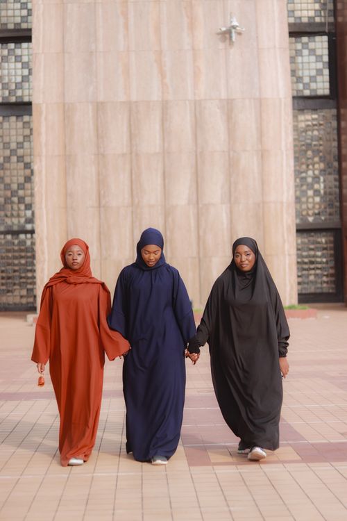 Free Three women in colorful traditional garments walking together outside, symbolizing unity and culture. Stock Photo