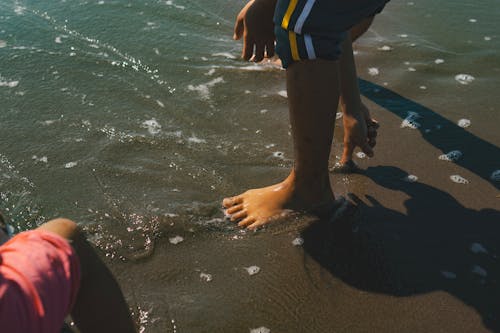 Free A child's feet in the water with sand Stock Photo