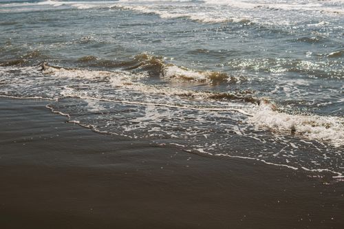 Free Peaceful scene of ocean waves softly washing over a sandy beach, perfect for summer travel inspiration. Stock Photo