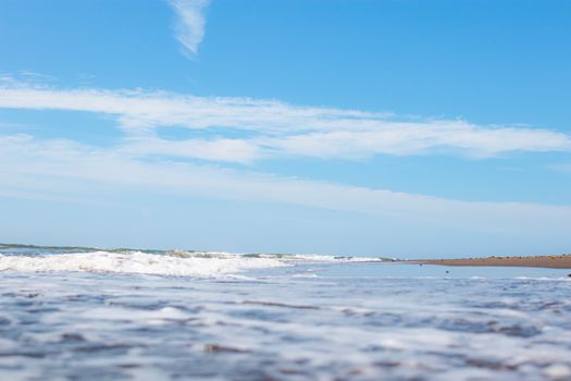 A peaceful beach view with gentle waves and clear blue sky, capturing a serene coastal atmosphere.
