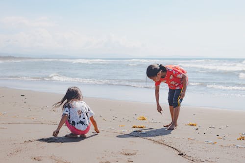 Two children playing on the beach with sand