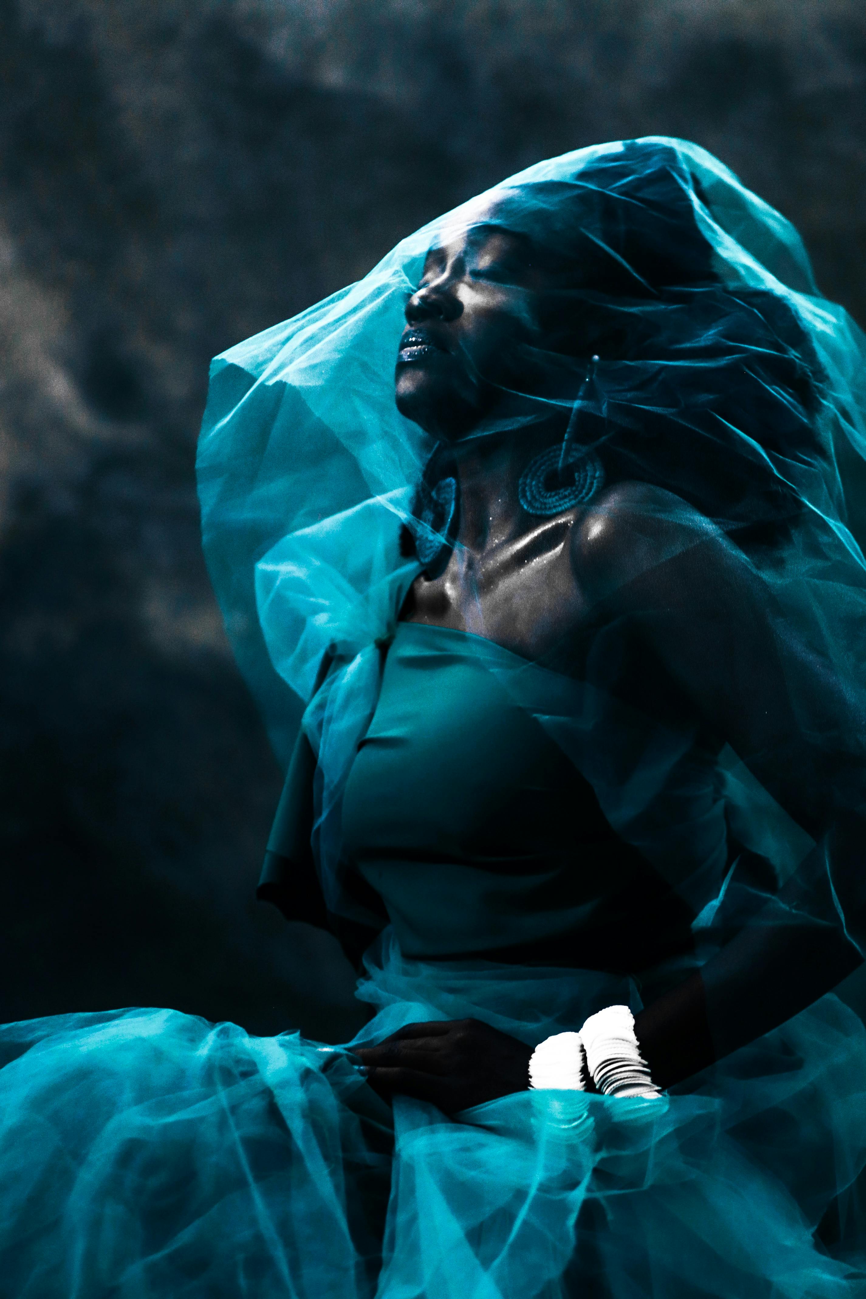 Striking portrait of a woman enveloped in a blue veil, expressing mystery and elegance.