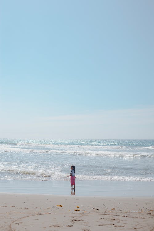 A person standing on the beach looking out at the ocean