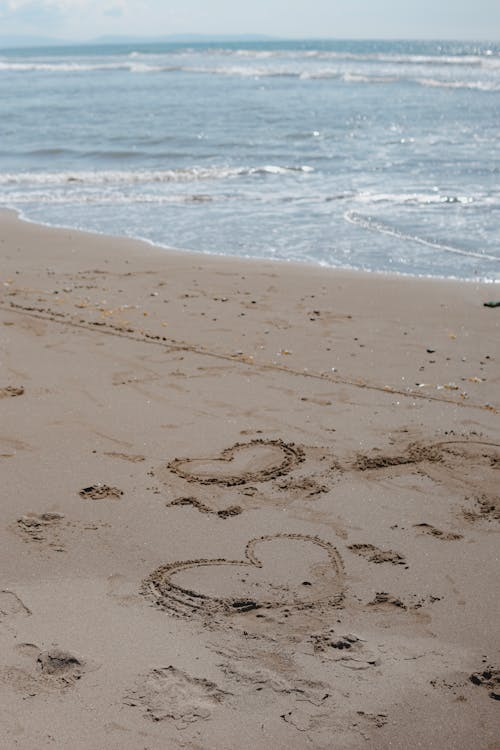 A beach with footprints in the sand and a heart drawn in the sand