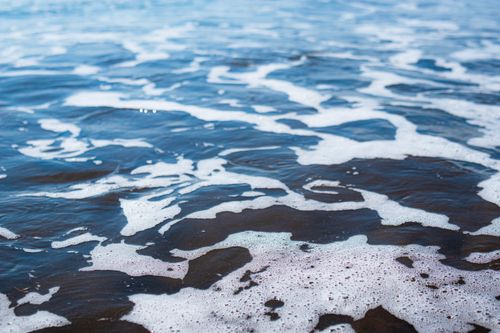 Free Close-up of gentle ocean waves displaying natural foam patterns along the shoreline. Stock Photo