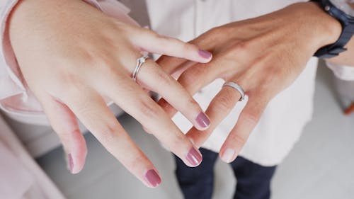 Two people holding hands with wedding rings on their fingers