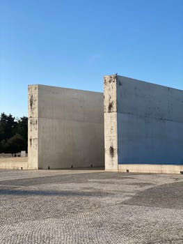 Stark concrete walls in urban setting against clear blue sky, Fátima, Portugal.