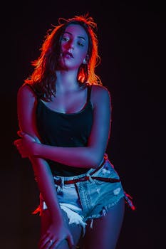 Striking portrait of a woman in trendy jean shorts with vibrant lighting creating an artistic effect.