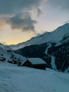 Snow-covered cabin in a serene mountain landscape during a beautiful winter sunset. 20110234