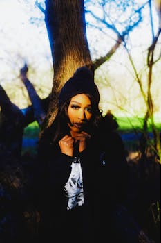 Dramatic outdoor portrait of a woman against a tree, creating a mysterious vibe.