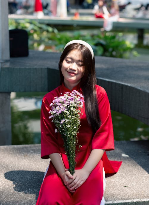 Beautiful Brunette Woman in Red Dress Posing with Bouquet of Flowers