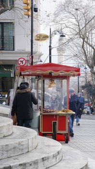 A vibrant street scene in Istanbul featuring a vendor cart selling roasted chestnuts on a busy city street.