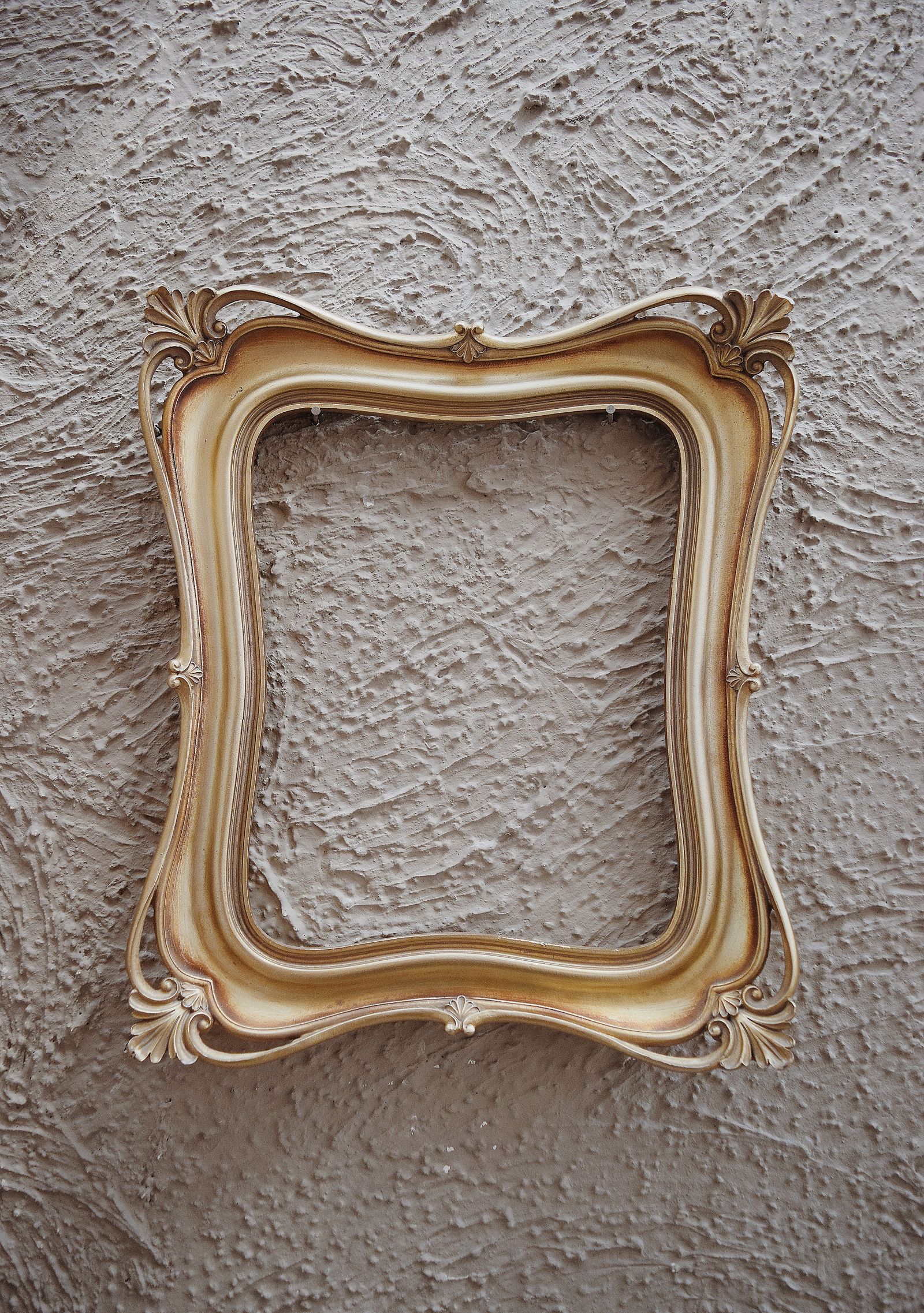 An ornate gilt frame holding a landscape, hung on a gallery wall