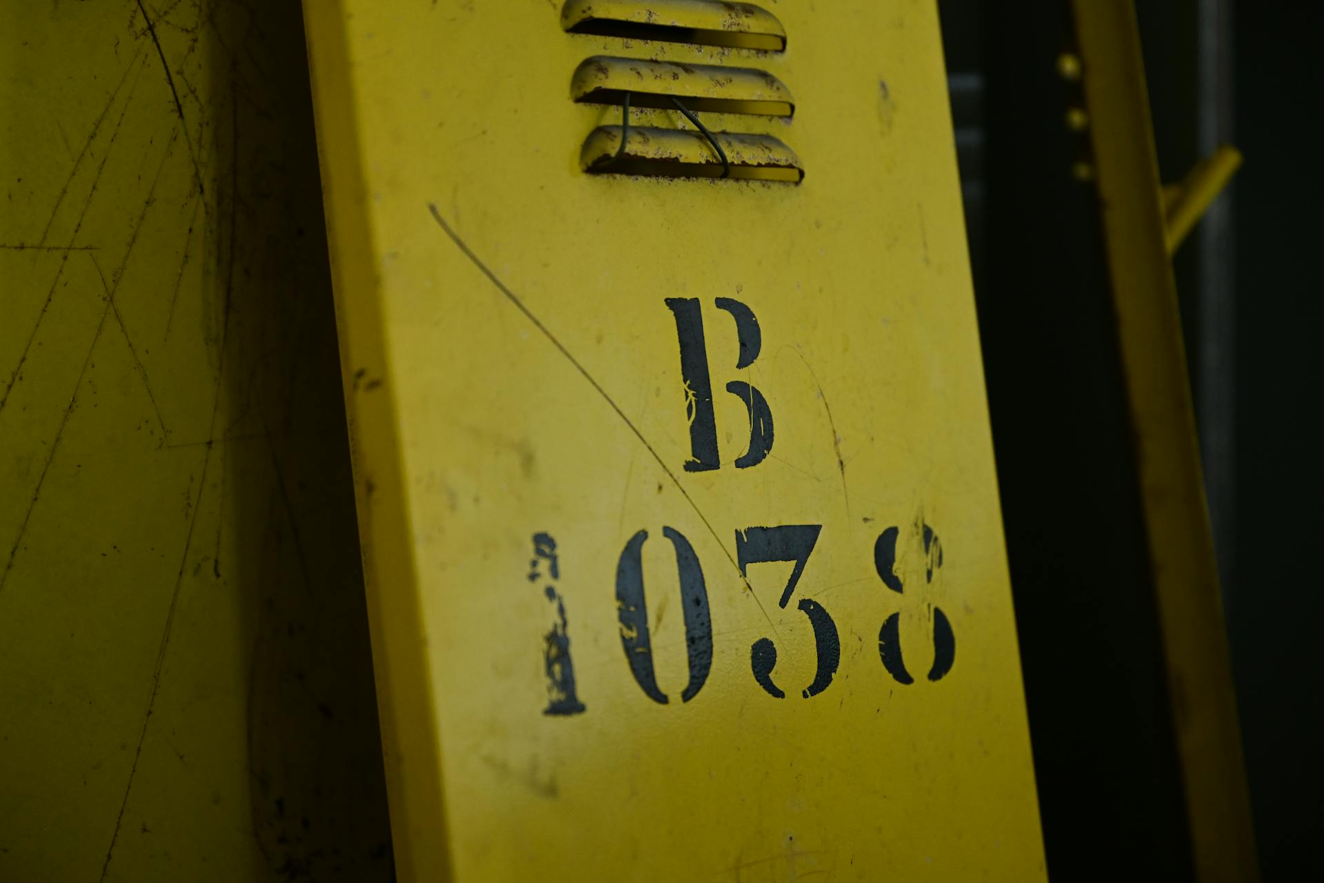 Detailed view of a vintage yellow industrial sign featuring the number 1038 and letter B.