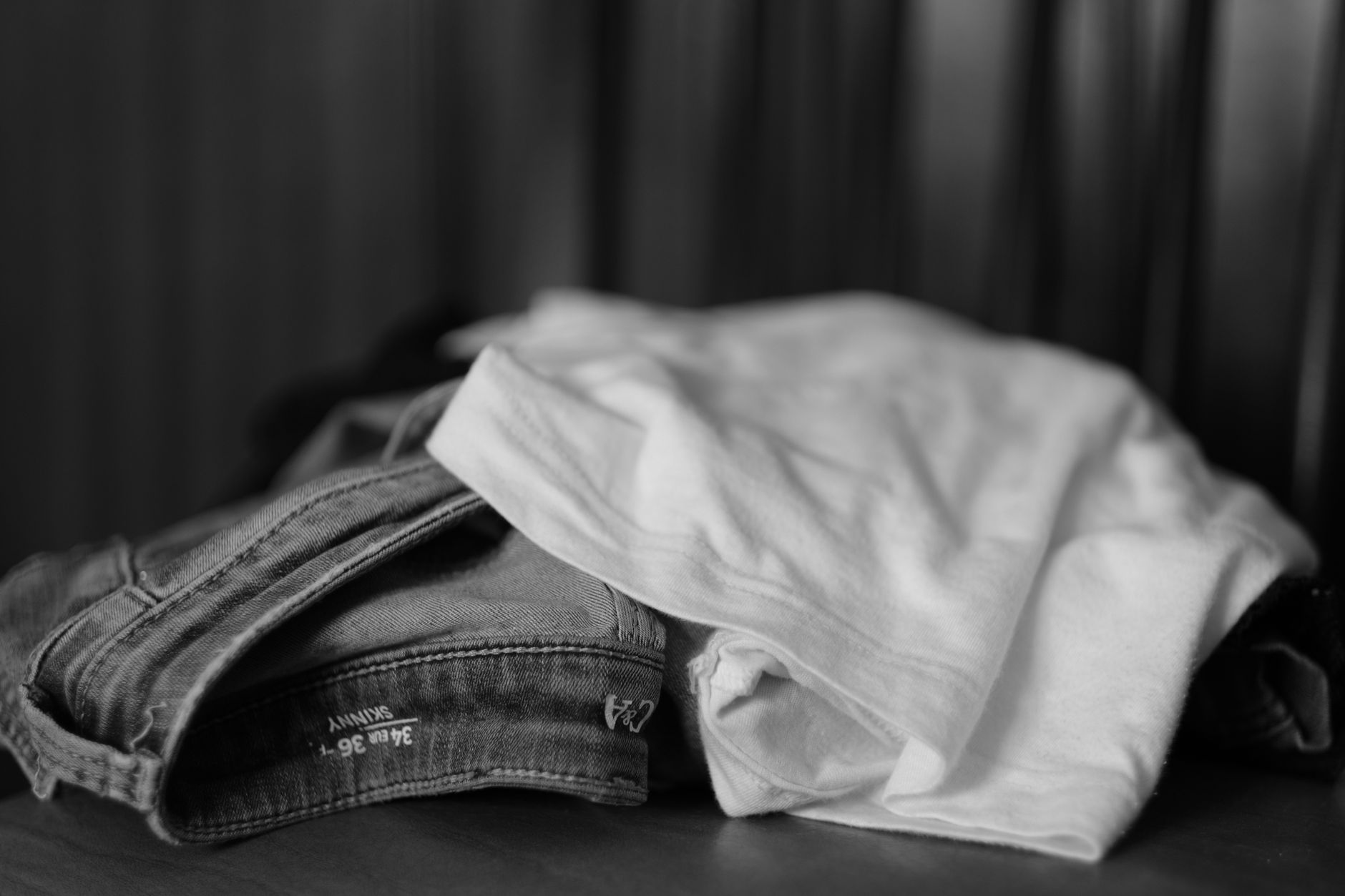Monochrome image showcasing a close-up of folded jeans and t-shirt.