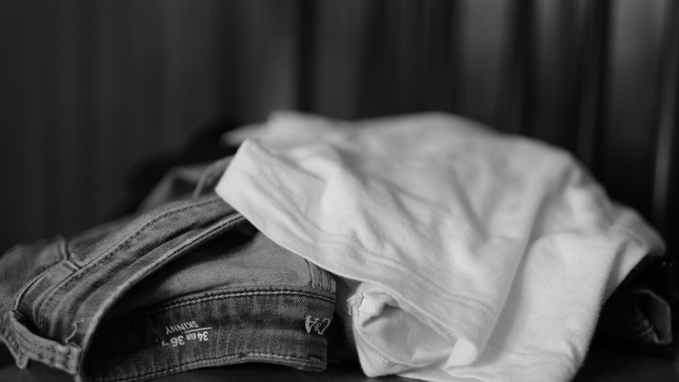 Monochrome image showcasing a close-up of folded jeans and t-shirt.