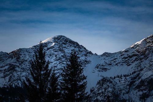 Free Stunning view of snow-covered mountain peaks and trees silhouetted in winter. Stock Photo