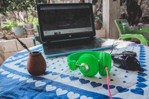 Free Green Corded Headphones Beside Blue and Black Laptop Computer Stock Photo