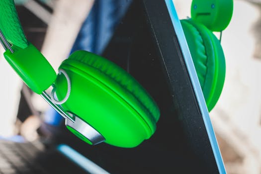 Close-up of vibrant green headphones resting against a modern laptop screen indoors.