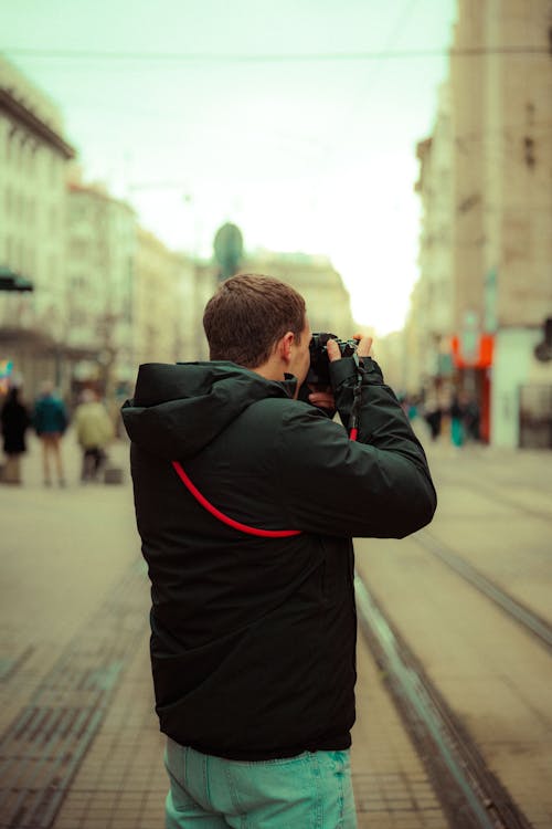 Man Holding a Camera on a Street 