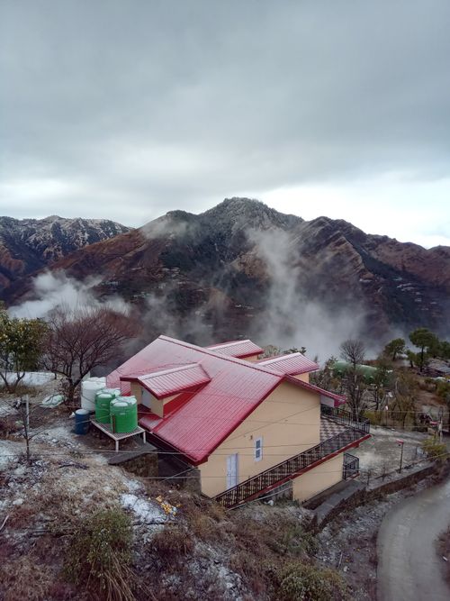 Free Scenic view of a red-roofed house in misty hills of Shimla, India. Stock Photo
