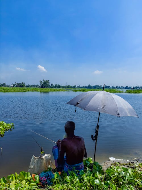 Fisherman Sitting under Umbrella and Fishing