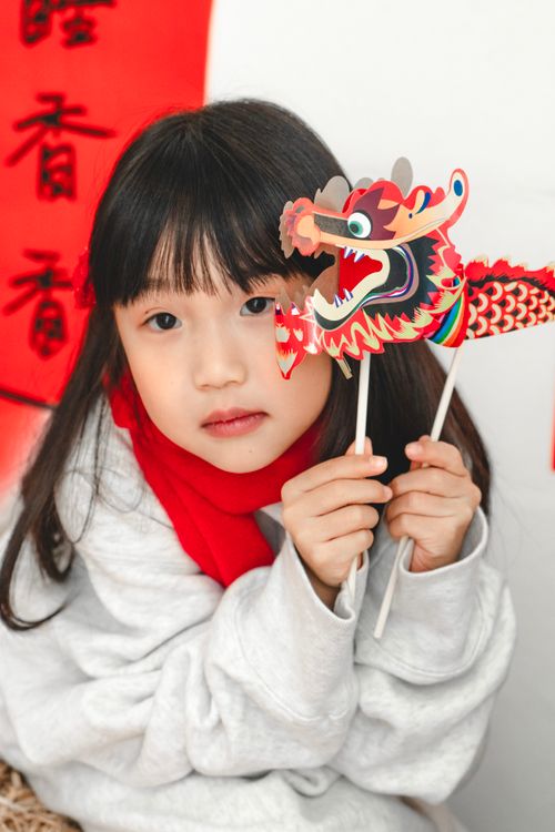 Free A child holds a colorful dragon stick, showcasing traditional festival decorations. Stock Photo