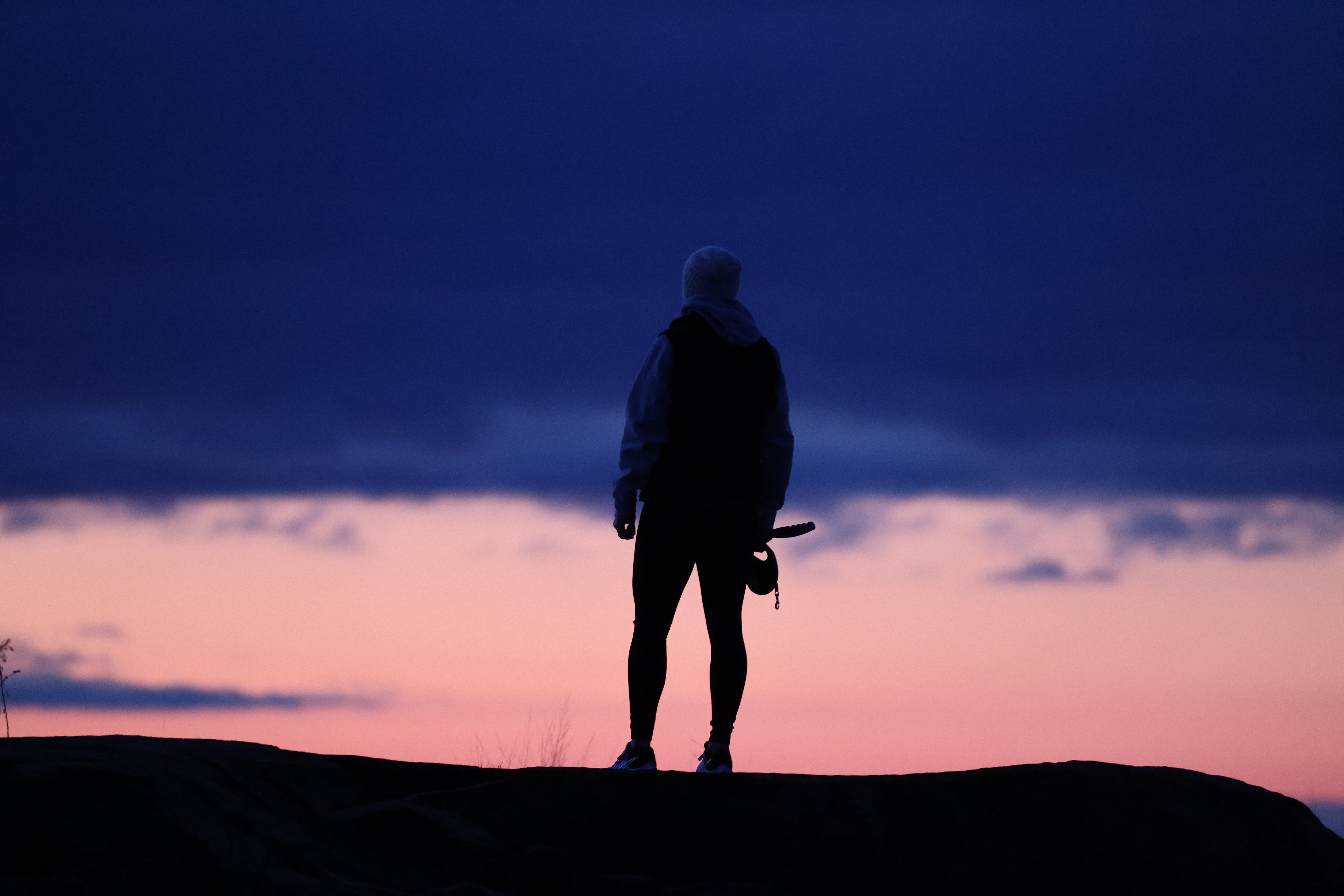 A serene view of a lone hiker silhouetted against a twilight sky in Stamford, CT.