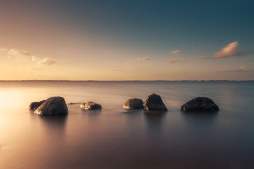 Long Exposure of a Calm Water Surface with Rocks near the Shore 