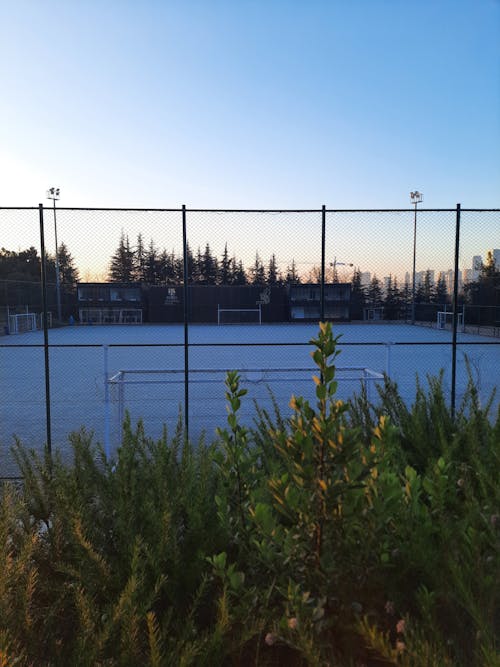 A fence with a tennis court in the background