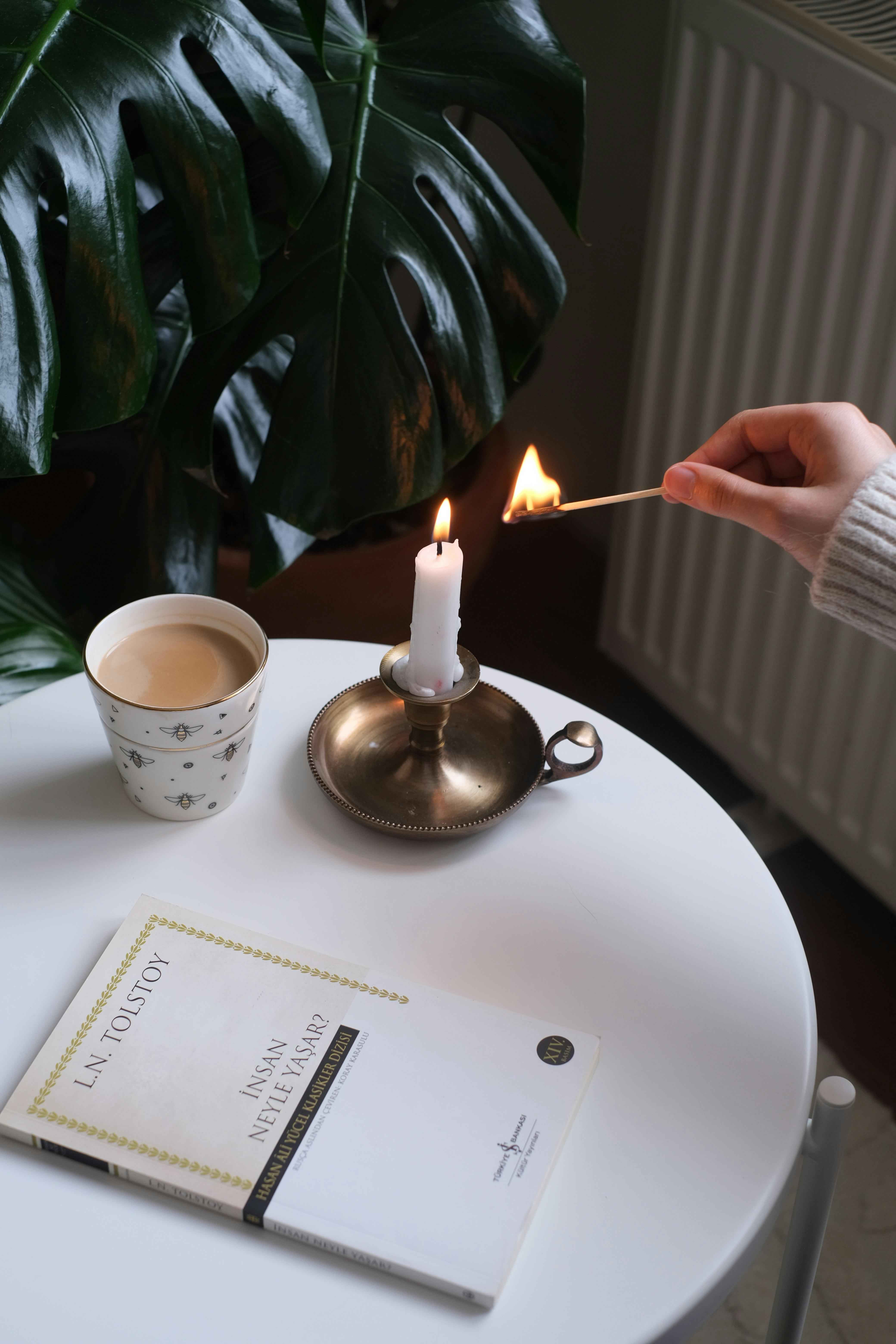A relaxing indoor scene with a candle, coffee, and a book on a table.