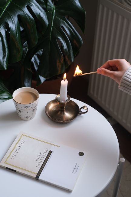 A relaxing indoor scene with a candle, coffee, and a book on a table.