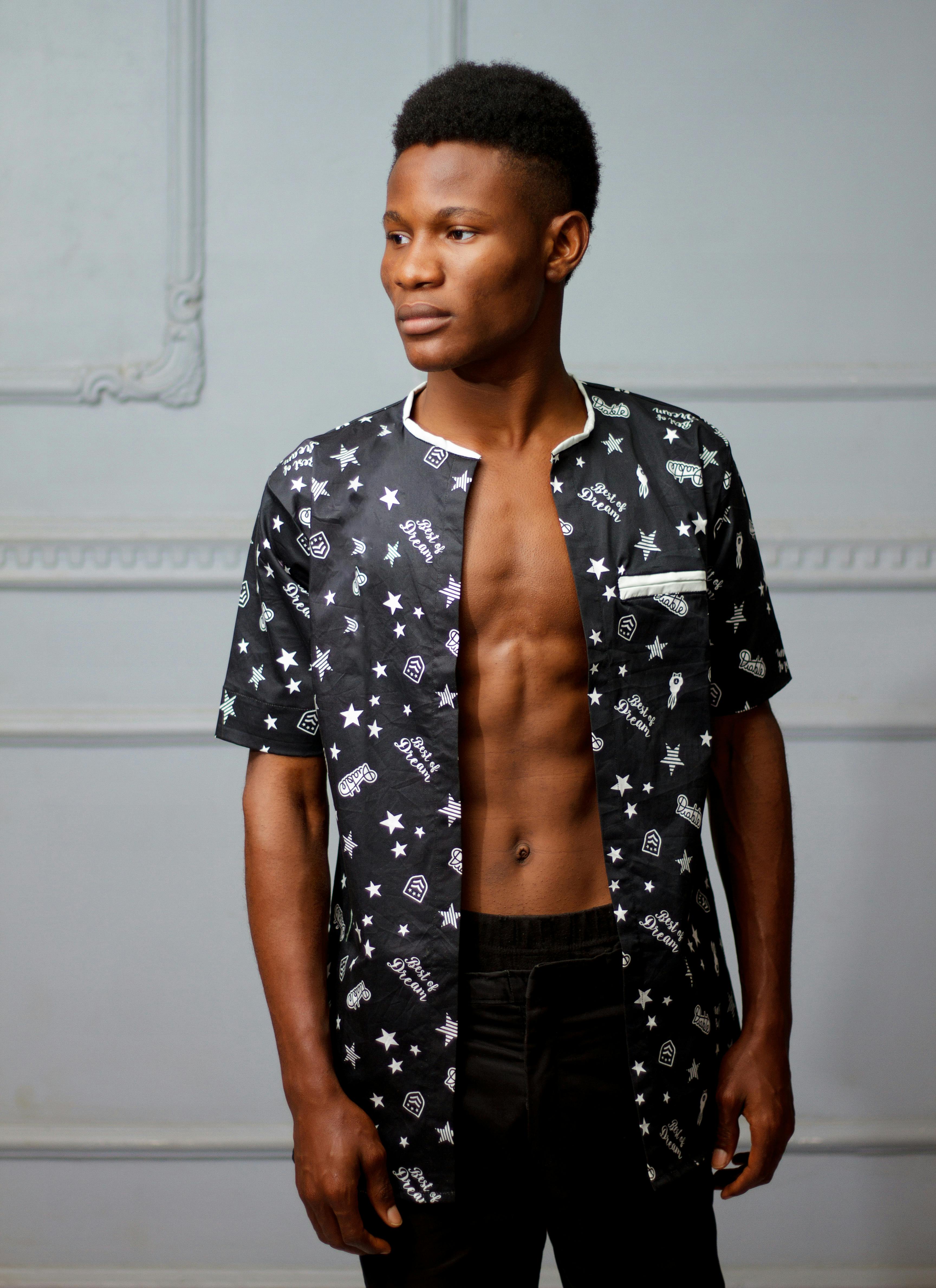 一位自信的年轻人身着时尚开襟衬衫，在室内摆出姿势，展现出兼具现代风格与优雅的气质