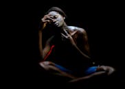 一幅表现主义肖像描绘了在黑暗中画着脸的女人，展现了她的情感与孤独