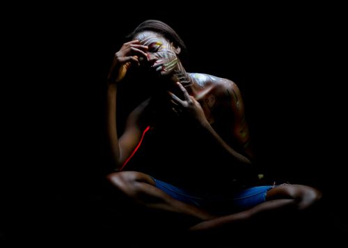 Free Expressionistic portrait of a woman with face paint in dark setting, showcasing emotion and solitude. Stock Photo