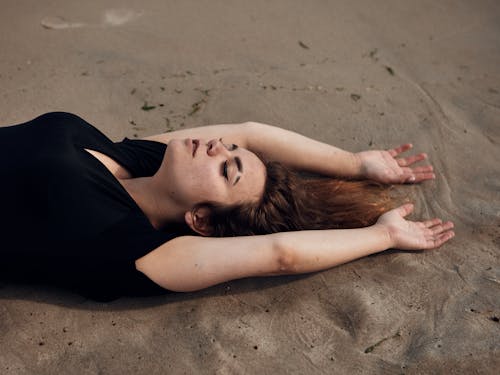 Free Young Woman Lying on a Beach with Eyes Closed  Stock Photo