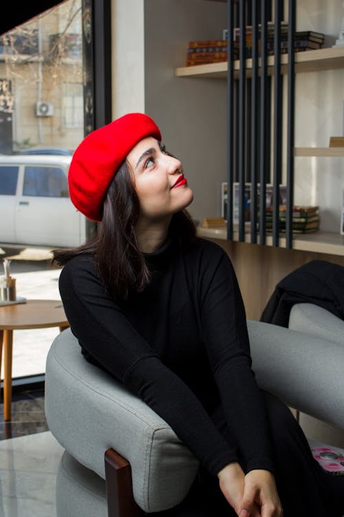 A woman wearing a red beret sits in a chair