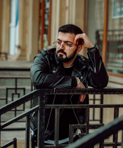 Free Man with a beard and eyeglasses leaning on railings in an urban setting in Baku, Azerbaijan. Stock Photo