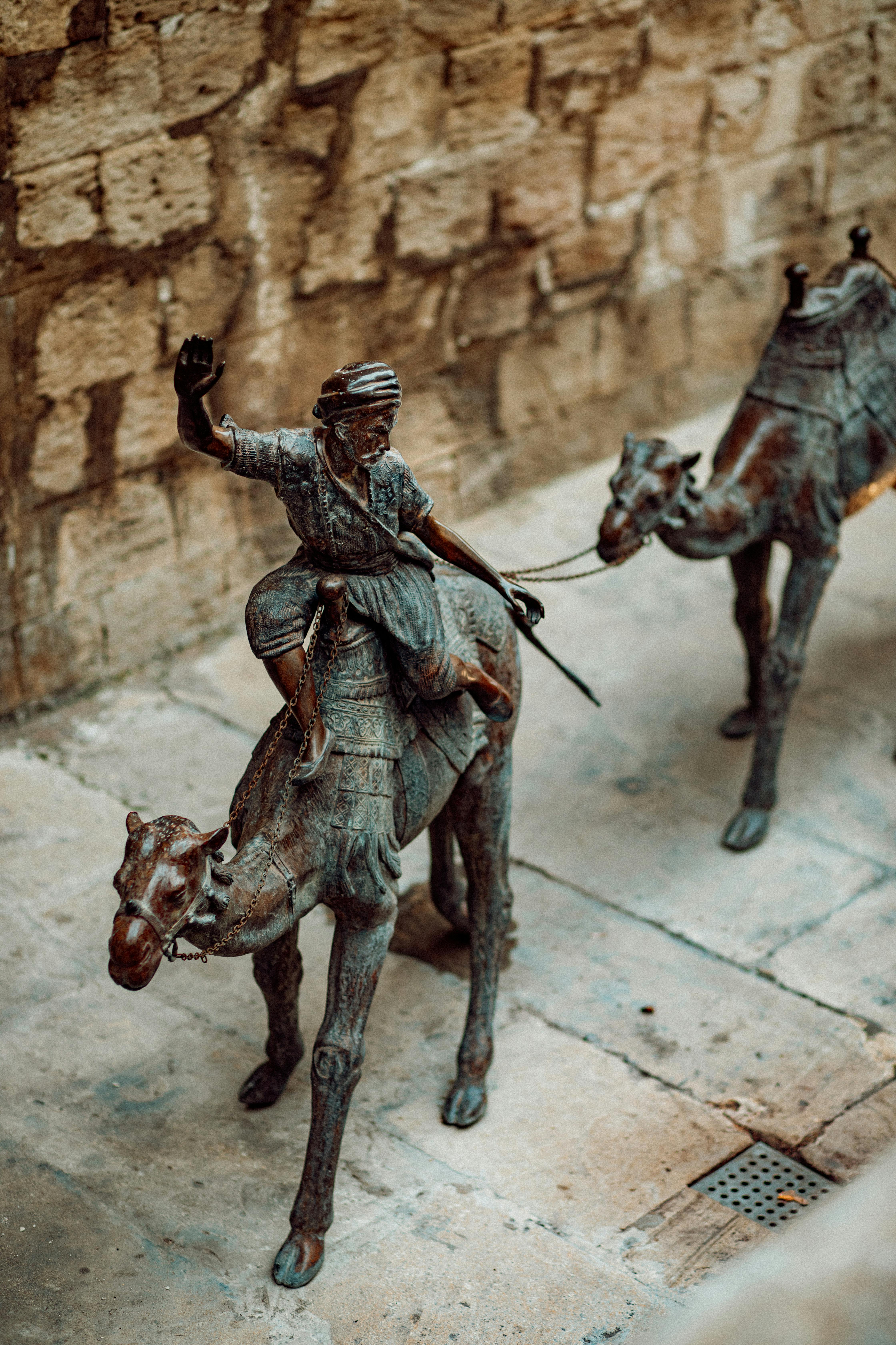 Two statues of men riding camels in a courtyard · Free Stock Photo