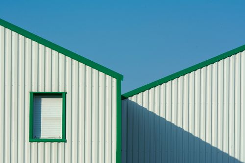 Free Minimalist building exterior with green accents under a clear blue sky. Stock Photo